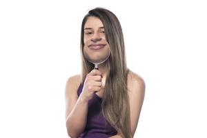 Laughing woman holds a magnifying glass in front of her mouth photo