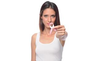 Female health check awareness. Closeup of young woman in pullover holding pink ribbon, symbol of breast cancer, timely diagnosis, support of oncology patients photo