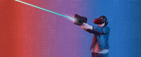 Hispanic woman wearing virtual reality goggles holding her gaming pistol with both hands, shooting straight up, illuminated with blue, red light against a virtual background photo