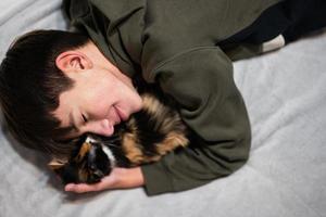 Teenager boy with kitty lying on the sofa. Children's love for pets. photo