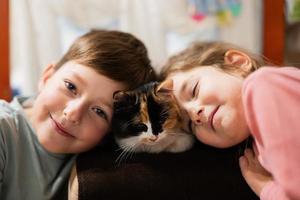 Brother and sister with kitty cat. Children's love for pets.
