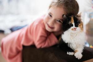 Baby girl with kitty lying on the sofa. Children's love for pets. photo