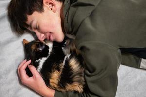 Teenager boy with kitty lying on the sofa. Children's love for pets. photo
