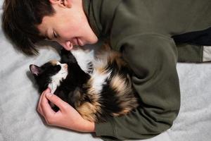 Teenager boy with kitty lying on the sofa. Children's love for pets. photo