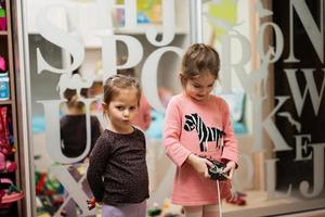 dos hermanas juegan con el control remoto en la habitación de los niños. foto