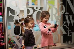 Two sisters play remote control in children's room. photo