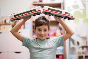 niño sostenga el tren de alta velocidad de juguete en las manos en la habitación de los niños. foto