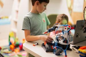 niños aprendiendo a reparar obteniendo un brazo de robot de control de lección, brazo de máquina robótica en taller doméstico, educación científica futura de tecnología. foto