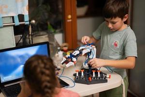 Children learning repairing getting lesson control robot arm, robotic machine arm in home workshop, technology future science education. photo