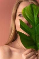Beautiful woman with a smooth skin holding green tropical leaf photo