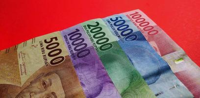 Closeup view of Indonesian 5000, 10000, 20000, 50000 and 100000 rupiah banknote isolated on red background. photo