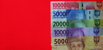 Indonesian 5000, 10000, 20000, 50000 and 100000 rupiah banknote isolated on red background. Free space background photo