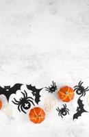 Vertical halloween background with skulls,pumpkins,bats abd spiders on white concrete. Invitation or card for october 31.Copy space photo