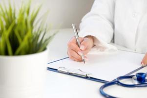 Front view at unrecognizable doctor using calculator with laptop and stethoscope near. Medical insurance concept photo