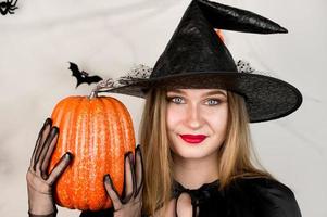 Autumn holidays banner with closeup of cute witch holding pumpkin on white background,. October 31 concept.Halloween party photo