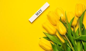 tarjeta de felicitación de primavera con tulipanes y mayo escrito en bloque de madera. banner de espacio de copia foto