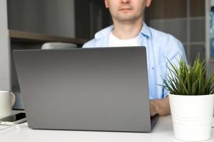 Young asian male working on laptop wearing.Remote work or education.Selective focus on laptop photo