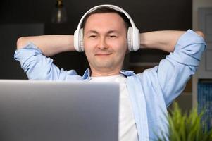 hombre asiático feliz con auriculares mirando la pantalla escuchando conferencias, curso foto