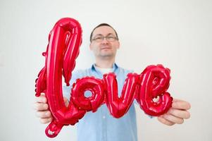 concepto de día de san valentín con hombre feliz con globo de amor. enfoque selectivo en globo. foto