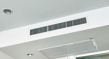 aire acondicionado tipo casete montado en el techo y luz de lámpara moderna en el techo blanco. Aire acondicionado por conductos para casa, recibidor u oficina. foto