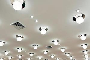 Ceiling mounted cassette type air conditioner and modern lamp light on white ceiling. Duct air conditioner for home, hall or office. photo