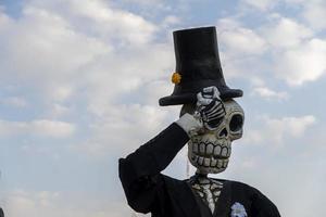 giant paper skulls dressed in black costume in the background blue sky with clouds photo