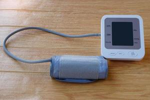 Digital blood pressure equipment with blank screen  on brown wooden floor. Blank screen of monitor for text. Concept, health care, hospital, clinic, doctor. Medical measurement tool for health check. photo