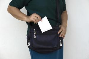 Closeup woman holds sanitary pad for menstruation to put into bag before going out. Concept, female's hygienic product for period's day. Woman healthcare. Monthly intimate hygiene. photo