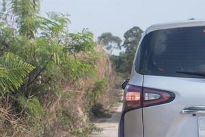 un coche blanco aparcado junto a un árbol en la carretera en un campo. foto