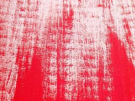 Artistic abstract background with acrylic or gouache red paint on textured canvas paper. Brushstrokes of red paint. Horizontal perspective backdrop with copy space. Selective focus, close up. photo