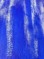 Artistic background with acrylic or gouache blue paint on textured canvas paper. Brushstrokes of dark blue paint. Vertical perspective abstract backdrop with copy space. Selective focus, close up. photo