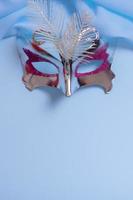 Festive face mask for carnival or masquerade celebration on colored background. Carnival background top view, flat lay photo