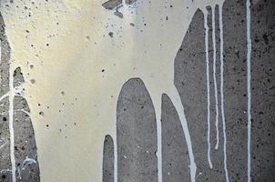 A photograph of a close-up of black paint spots on a concrete wall. Pouring paint on the wall in random order. The concept of graffiti and street art culture photo