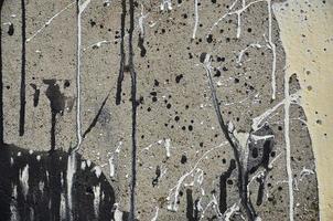 A photograph of a close-up of black paint spots on a concrete wall. Pouring paint on the wall in random order. The concept of graffiti and street art culture photo