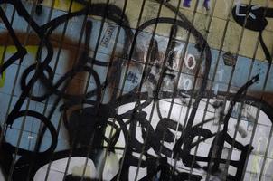 A fragment of graffiti drawing and a set of tags applied to the wall from the old tile in the subway tunnel. The concept of street art and vandalism photo
