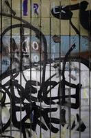 un fragmento de dibujo de grafiti y un conjunto de etiquetas aplicadas a la pared del antiguo azulejo del túnel del metro. el concepto de arte callejero y vandalismo foto