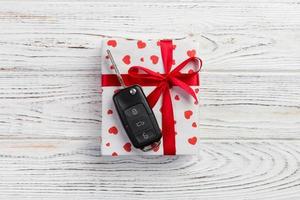 Valentine or other holiday handmade present in paper with red hearts, car keys and gifts box in holiday wrapper. box gift on white wooden table top view with copy space, empty space for design photo