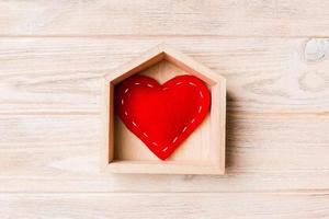 vista superior del corazón textil rojo en una casa sobre fondo de madera. concepto de hogar dulce hogar. día de San Valentín foto