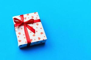 Background with gift box and hearts on blue Background. Top view with copy space for text photo