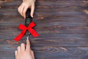 Woomen give car key. Woman hand hold car key with red bow. Giving a car as a gift photo