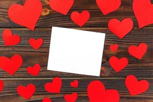 nota de papel en blanco con forma de corazón rojo sobre fondo de madera grunge foto