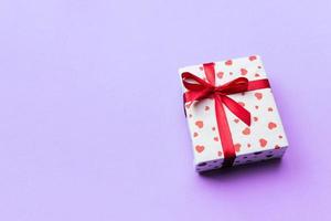 Background with gift box and hearts on purple Background. Top view with copy space for text photo