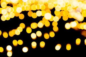 Festive abstract gold background with bokeh defocused and blurred many round yellow light on Christmas dark background photo