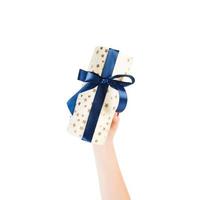 Woman hands give wrapped Christmas or other holiday handmade present in gold paper with blue ribbon. Isolated on white background, top view. thanksgiving Gift box concept photo