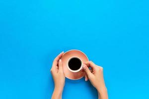 Minimalistic style woman hand holding a cup of coffee on background. Flat lay, top view photo