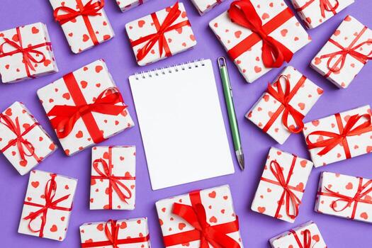 Holiday composition of notebook and gift boxes with red hearts on colorful background with empty space for your design. Top view of Valentine's Day concept photo