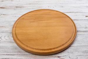 Wooden round empty board for pizza on wood table background, top view. Mockup for menu, recipe or any dish. Vertical image photo