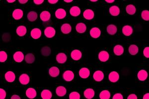 Bokeh rosa abstracto desenfocado sobre fondo negro. desenfocado y borroso muchas luces redondas foto
