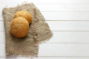 baked bun with sesame seeds lying on fabric photo