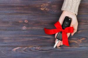 Woman hand hold car key with red bow. Giving a car as a gift photo